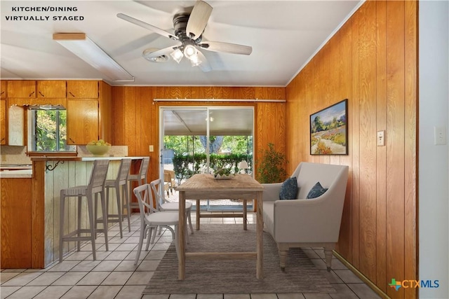 tiled dining room featuring ceiling fan, a wealth of natural light, and wooden walls