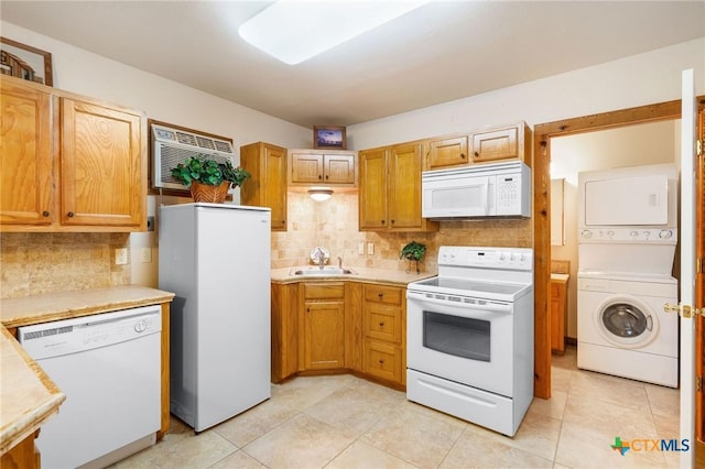 kitchen with stacked washer / drying machine, white appliances, sink, and backsplash