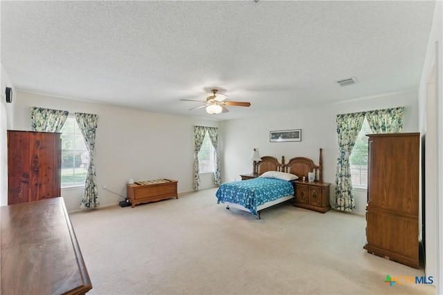 1233 Oakcrest Dr, Pleasanton, TX 78064 - carpeted bedroom with multiple windows, a textured ceiling, and a ceiling fan