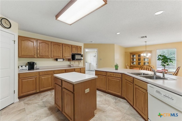 1233 Oakcrest Dr, Pleasanton, TX 78064 - kitchen featuring dishwasher, black microwave, a center island, light countertops, and brown cabinetry