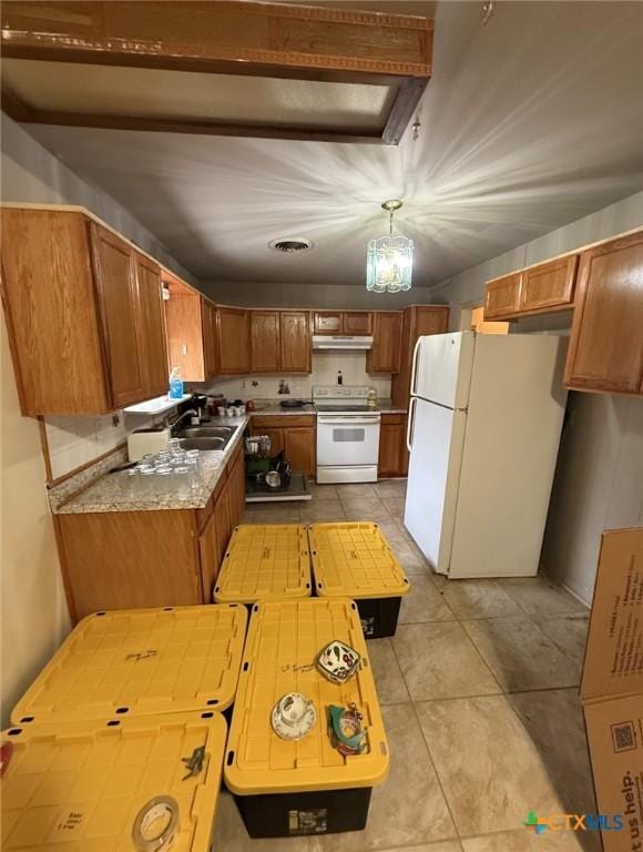 kitchen with brown cabinets, white appliances, light tile patterned flooring, and under cabinet range hood