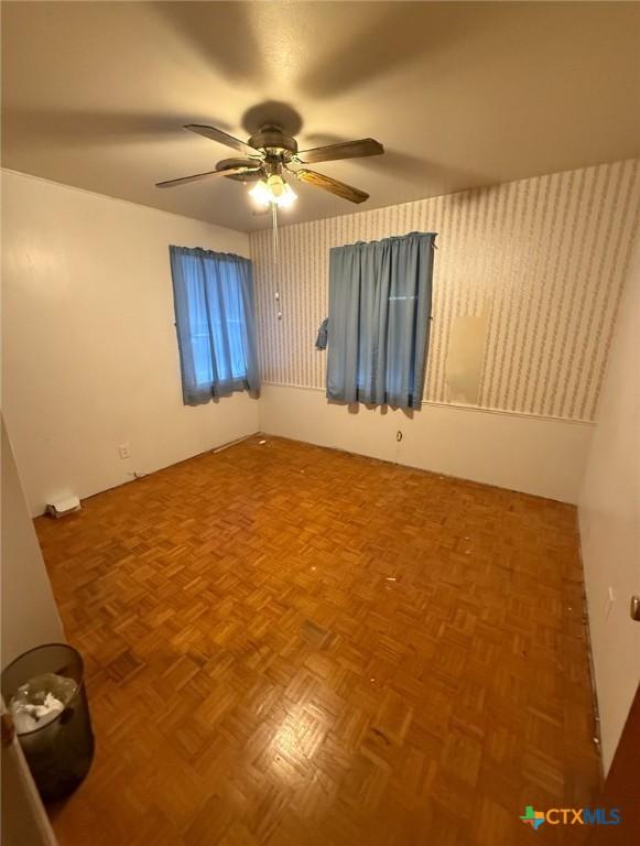 spare room with wallpapered walls and ceiling fan