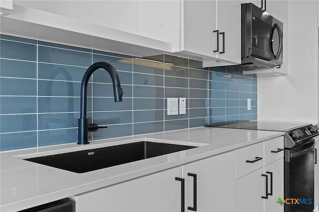 kitchen featuring white cabinets, range with electric cooktop, tasteful backsplash, and sink