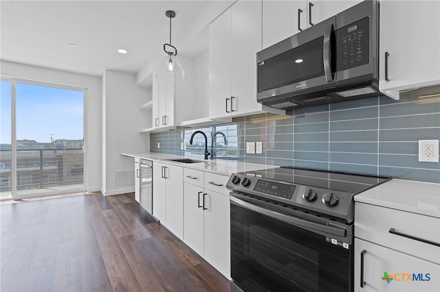 kitchen with backsplash, stainless steel appliances, dark wood-type flooring, sink, and hanging light fixtures