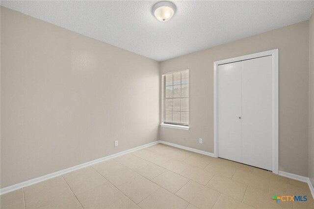 3317 Westrim Dr, Killeen, TX 76549 - unfurnished bedroom with baseboards, a textured ceiling, light tile patterned floors, and a closet