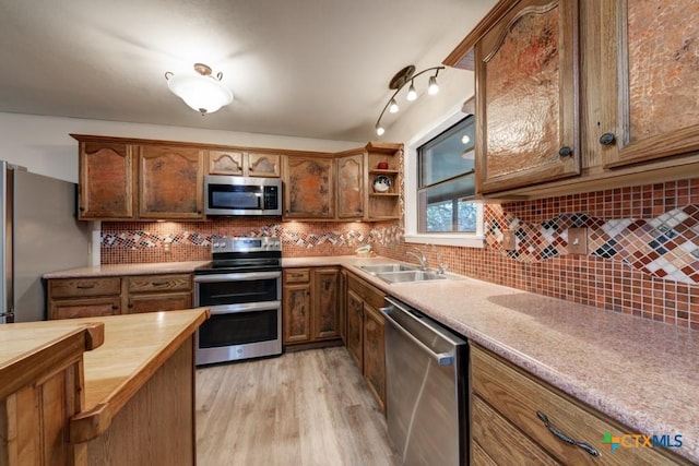 kitchen with backsplash, butcher block countertops, light wood-style flooring, stainless steel appliances, and a sink