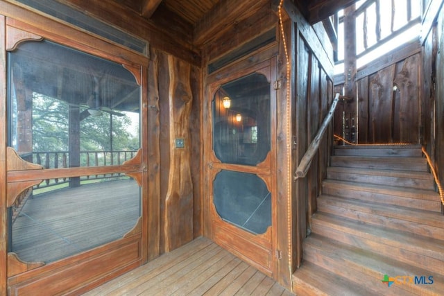 stairway featuring a wealth of natural light, wood walls, and hardwood / wood-style flooring