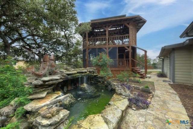 back of house featuring a balcony and a small pond