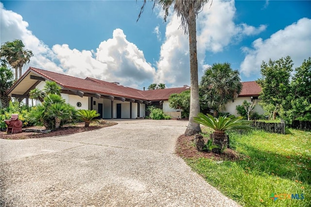 1809 W Harrison Ave, Port Oconnor, TX 77982 - view of front of house featuring stucco siding, a tiled roof, and curved driveway