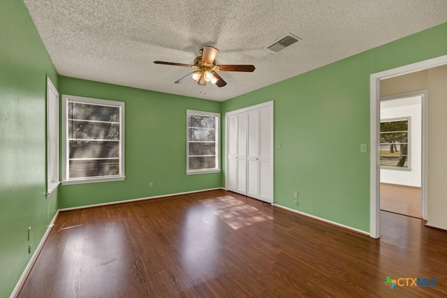 unfurnished bedroom featuring dark hardwood / wood-style flooring, a textured ceiling, a closet, and ceiling fan