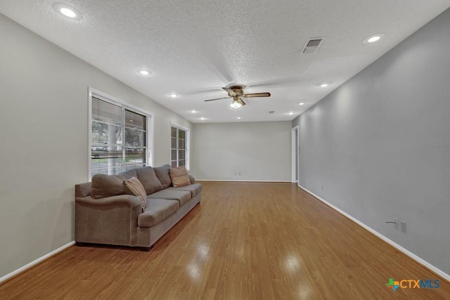 living room with ceiling fan, light hardwood / wood-style flooring, and a textured ceiling