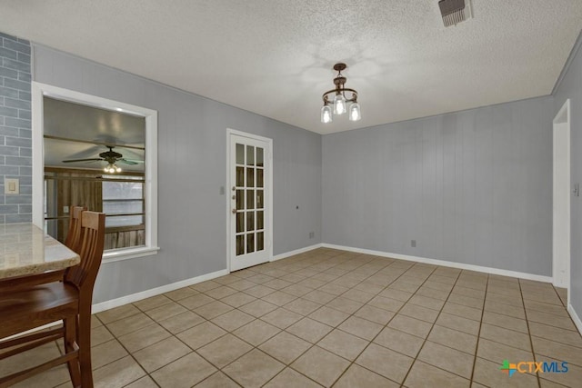 unfurnished dining area with ceiling fan with notable chandelier and a textured ceiling