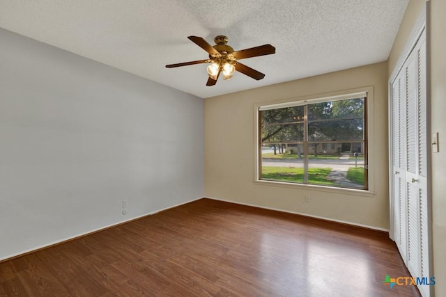 unfurnished bedroom featuring ceiling fan, dark hardwood / wood-style floors, a textured ceiling, and a closet