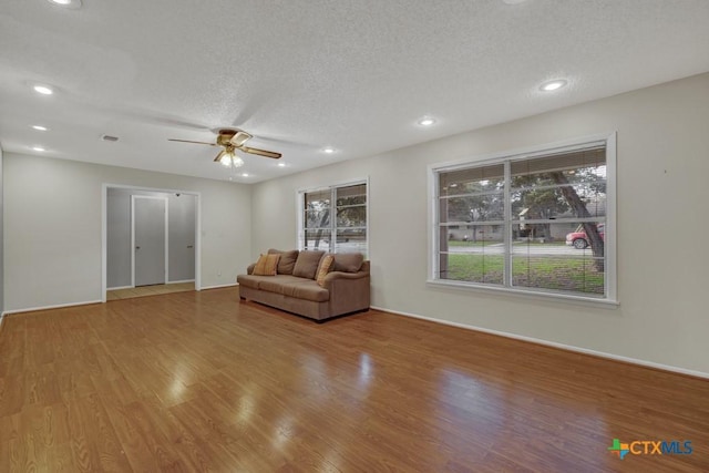 unfurnished living room with ceiling fan, hardwood / wood-style flooring, and a textured ceiling