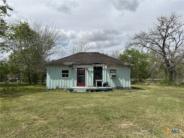back of house featuring a lawn, board and batten siding, and an outbuilding