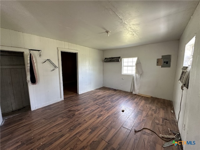 interior space featuring electric panel, dark wood finished floors, and wooden walls