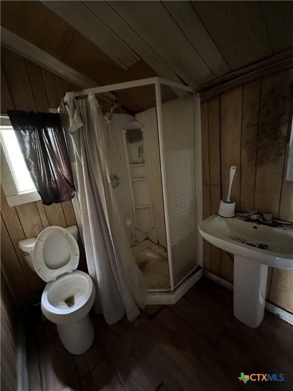 full bathroom featuring toilet, wood finished floors, a stall shower, vaulted ceiling, and wooden walls