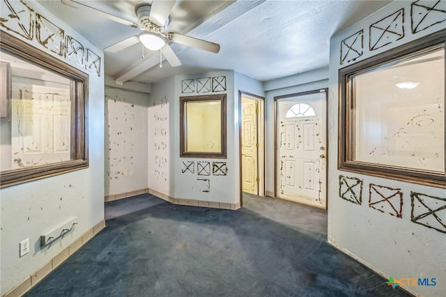 carpeted empty room featuring ceiling fan and a textured ceiling