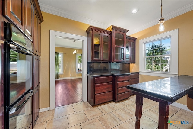 kitchen featuring ornamental molding, black double oven, hanging light fixtures, and light hardwood / wood-style floors