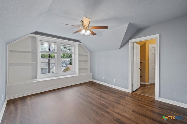 additional living space featuring built in features, dark wood-type flooring, a textured ceiling, and vaulted ceiling