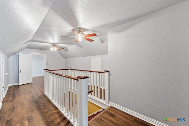 hallway featuring dark hardwood / wood-style flooring, lofted ceiling, and a textured ceiling