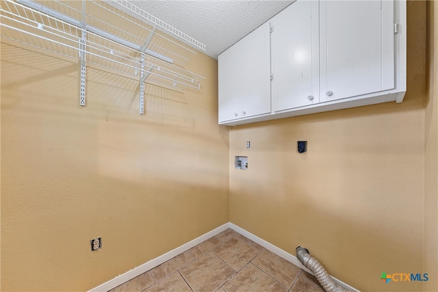 laundry area with light tile patterned flooring, hookup for an electric dryer, washer hookup, a textured ceiling, and cabinets