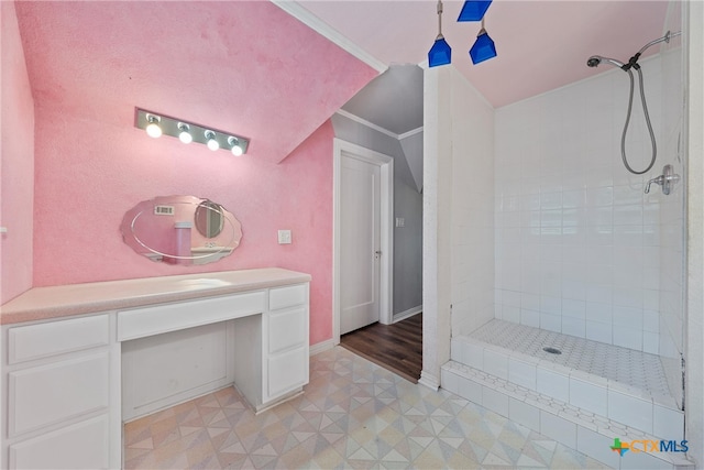 bathroom with crown molding, tile patterned flooring, vanity, and a tile shower