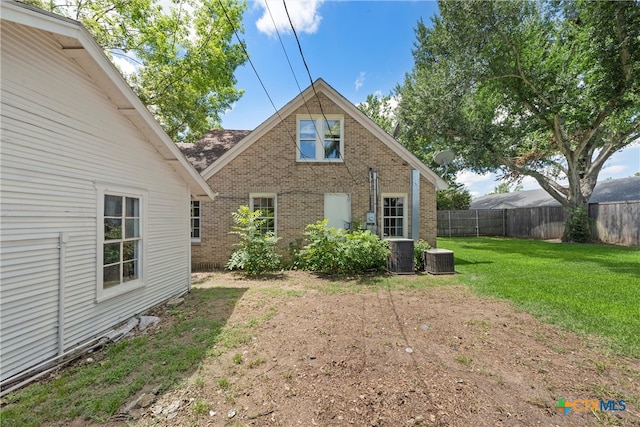 rear view of house with cooling unit and a lawn