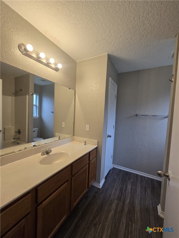 8630 Hogan Rd, Temple, TX 76502 - bathroom with a textured ceiling, wood finished floors, toilet, vanity, and baseboards