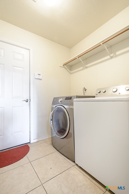 laundry room with light tile patterned floors and washer and clothes dryer