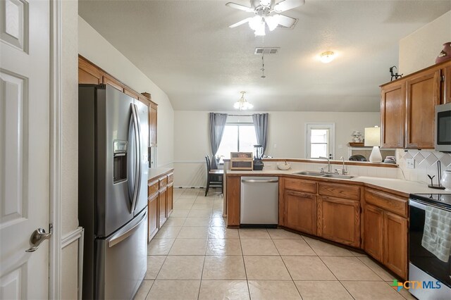 kitchen featuring stainless steel appliances, kitchen peninsula, decorative backsplash, sink, and light tile patterned floors