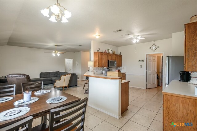 kitchen with ceiling fan with notable chandelier, stainless steel appliances, kitchen peninsula, hanging light fixtures, and light tile patterned floors