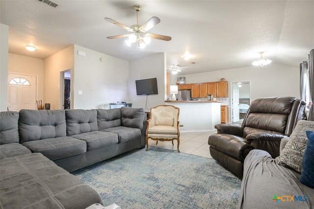 tiled living room with ceiling fan with notable chandelier