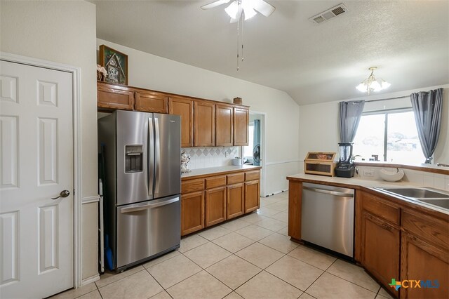 kitchen with tasteful backsplash, light tile patterned flooring, stainless steel appliances, sink, and ceiling fan with notable chandelier