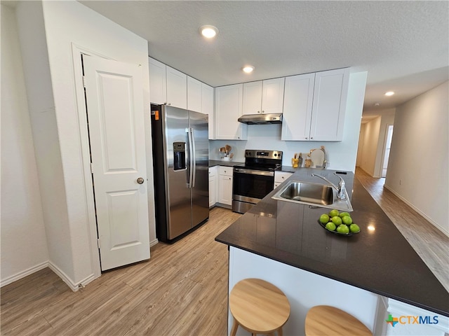 kitchen with white cabinets, sink, appliances with stainless steel finishes, light hardwood / wood-style floors, and kitchen peninsula