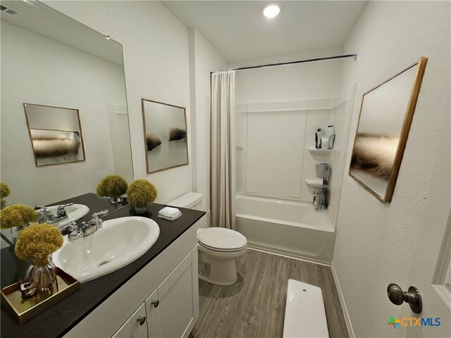 full bathroom with toilet, hardwood / wood-style floors, vanity, and shower / tub combo with curtain