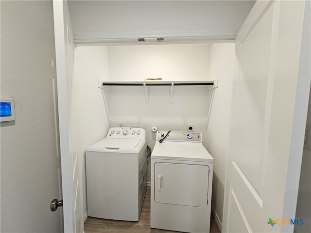 clothes washing area with washer and dryer and hardwood / wood-style flooring