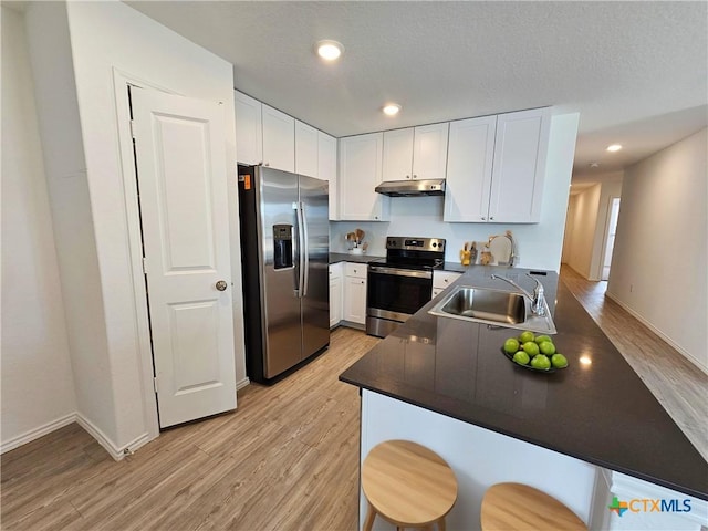 kitchen with sink, light hardwood / wood-style flooring, white cabinetry, kitchen peninsula, and stainless steel appliances