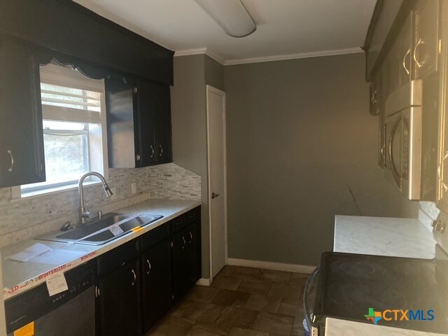 kitchen featuring decorative backsplash, appliances with stainless steel finishes, sink, and ornamental molding