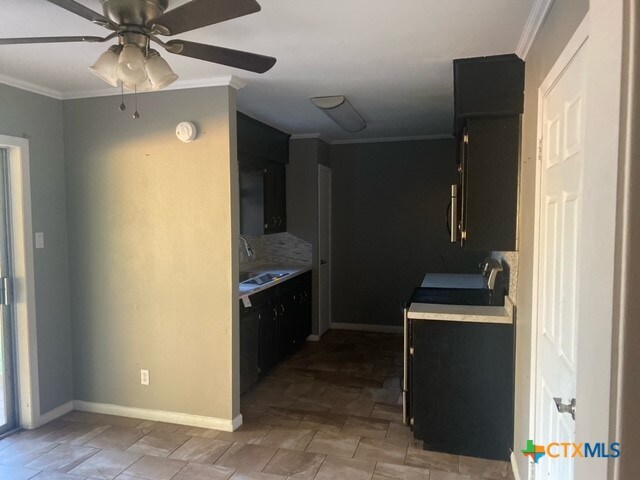 kitchen with ceiling fan, sink, stainless steel range, and ornamental molding