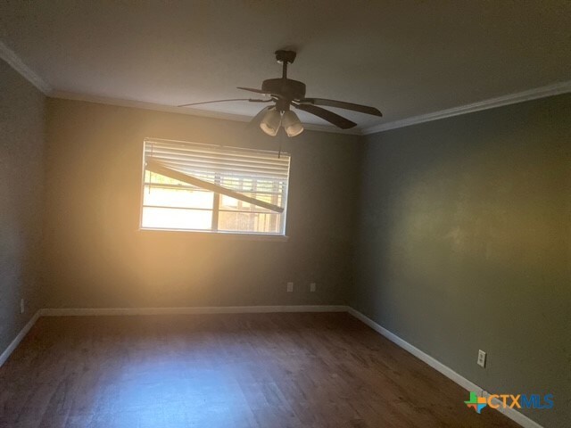 empty room with ceiling fan, wood-type flooring, and ornamental molding