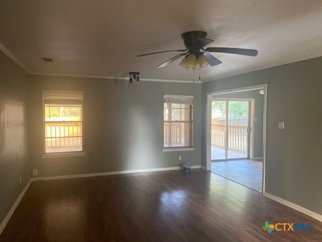 unfurnished room featuring a wealth of natural light, wood-type flooring, and crown molding