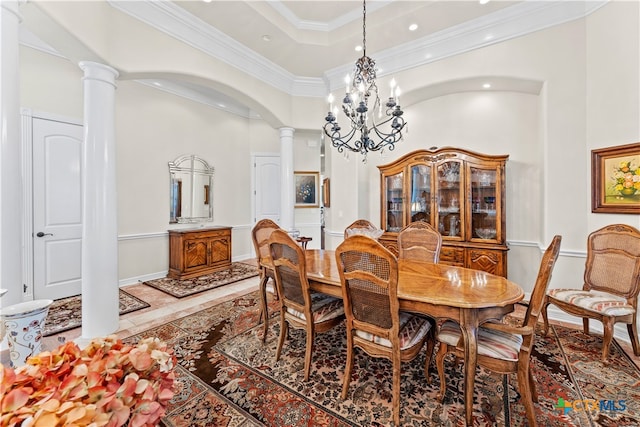 dining room with a high ceiling, ornamental molding, a notable chandelier, and ornate columns