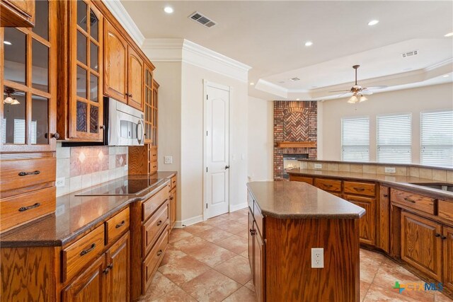 bedroom with ornamental molding, connected bathroom, dark hardwood / wood-style floors, a tile fireplace, and ceiling fan