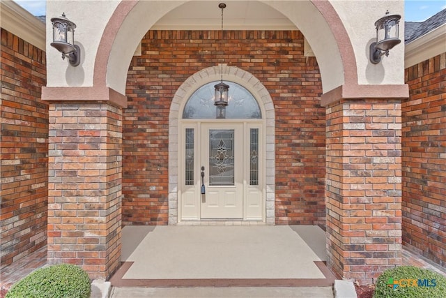 view of exterior entry with covered porch and brick siding