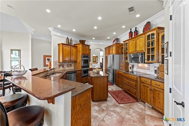 kitchen featuring stainless steel appliances, kitchen peninsula, a breakfast bar area, tasteful backsplash, and a kitchen island