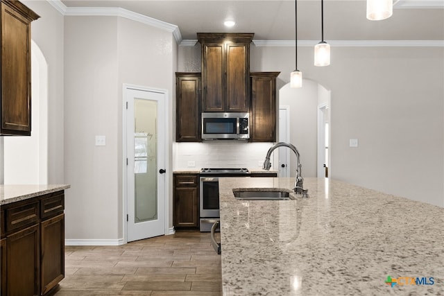 kitchen featuring tasteful backsplash, arched walkways, appliances with stainless steel finishes, wood tiled floor, and a sink