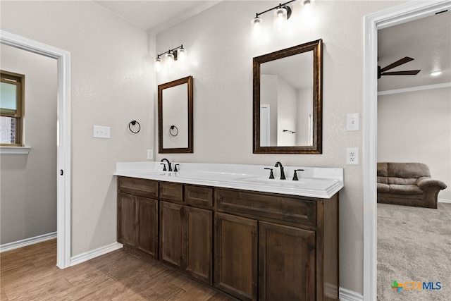 bathroom with double vanity, baseboards, a ceiling fan, wood finished floors, and a sink