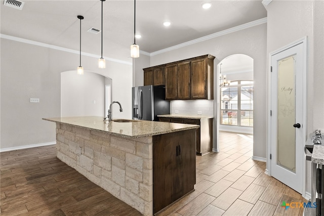 kitchen featuring arched walkways, a sink, stainless steel fridge with ice dispenser, and wood finished floors