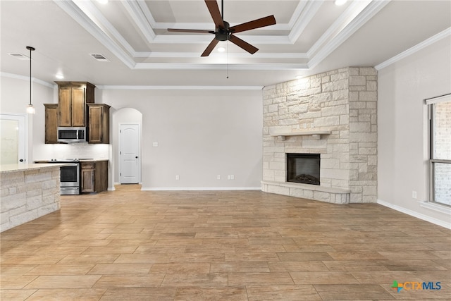 unfurnished living room featuring arched walkways, a stone fireplace, visible vents, a ceiling fan, and ornamental molding